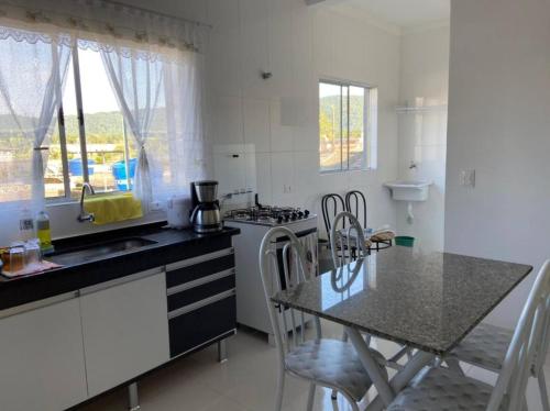 eine Küche mit einem Tisch, einer Spüle und einem Herd in der Unterkunft Casa na praia da enseada - Guarujá in Guarujá