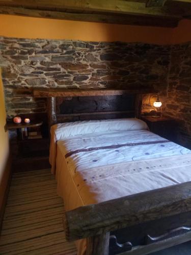 a bed in a room with a stone wall at Casas Eladio-Doncos in Torés