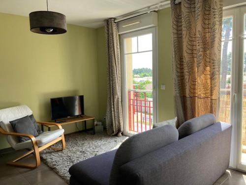 un salon avec un canapé, une télévision et une fenêtre dans l'établissement T2 dans quartier résidentiel sur le Bassin Arcachon avec location de vélos, à Gujan-Mestras