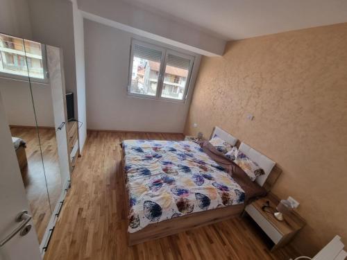 1 dormitorio con cama con edredón y ventana en Atena Apartment, en Ohrid