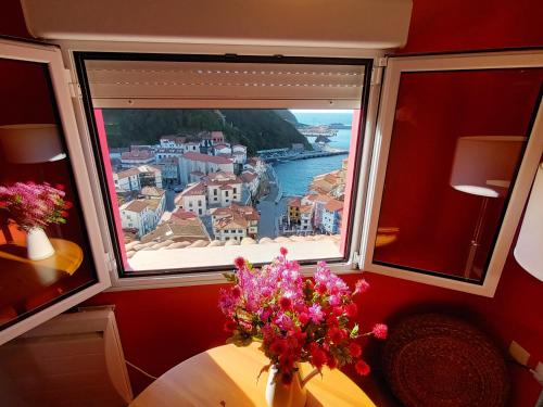 a window with a table and a view of the ocean at Apartamentos La Casa del Pintor in Cudillero