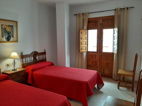 1 dormitorio con 2 camas rojas y ventana en Apartamento rural Boreal en Cómpeta