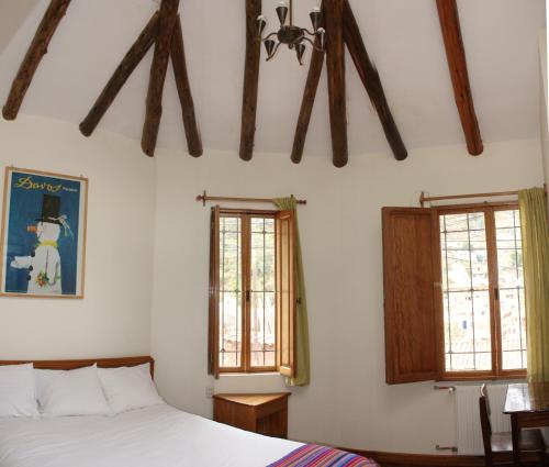 a bedroom with a bed and two windows at Maison Fortaleza in Cusco