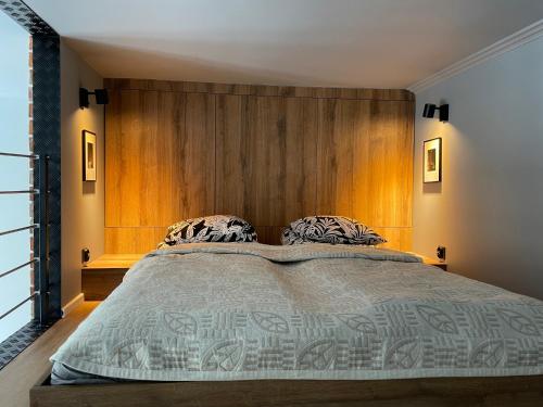 a bedroom with a large bed with a wooden headboard at OFF Side Story Apartment in Łódź