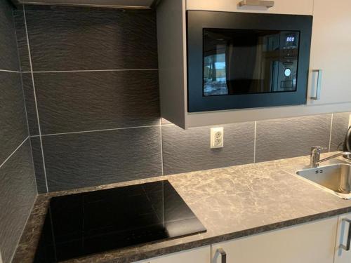 cocina con fregadero y TV de pantalla plana. en Huisje 96, en Exloo