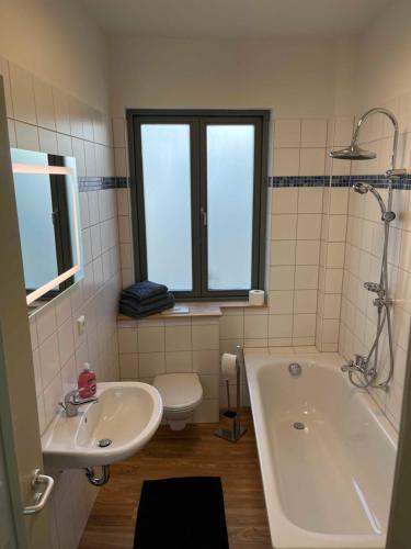 a bathroom with a tub and a sink and a toilet at Im Zentrum wohnen, Ruhe genießen in Greifswald