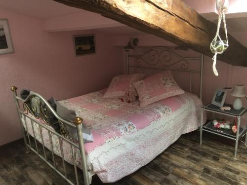 een slaapkamer met een bed met roze lakens en een houten vloer bij l'Ancienne Forge in Aigonnay