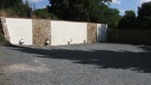a building with a stone wall next to a fence at Penzion V Roklich & Apartmens V Roklich in Ricany