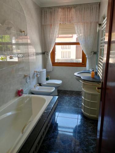 a bathroom with two toilets and a tub and a sink at Casa Cabaleiro in Seixo