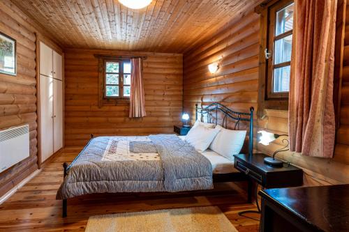 ein Schlafzimmer mit einem Bett in einer Holzhütte in der Unterkunft Chalet Likouresi Village in Karpenisi