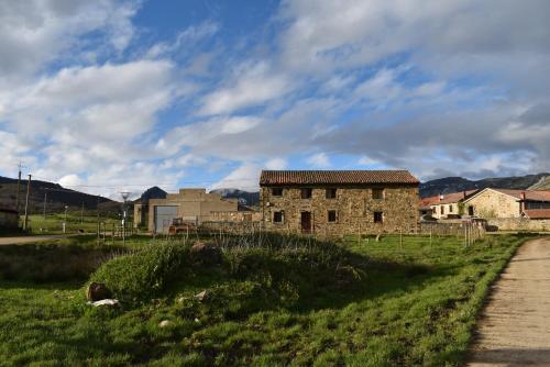 un antiguo edificio de piedra en un campo al lado de una carretera en Albergue Tremaya, en Lebanza
