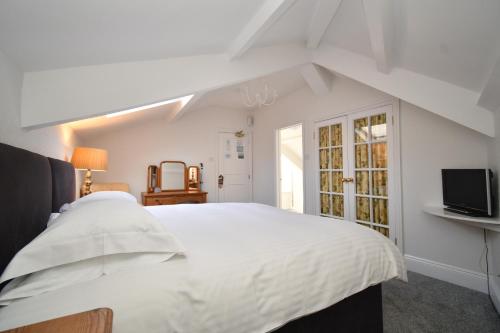 a bedroom with a white bed and a tv at Tenby House in Tenby