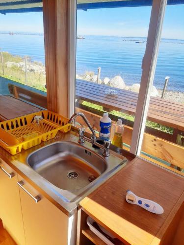 a kitchen with a sink and a view of the ocean at Hostal y Cabañas Mozart in Puerto Montt