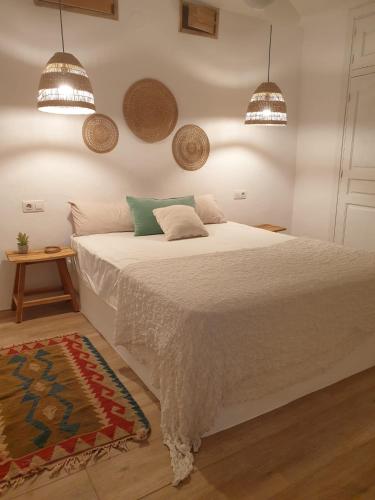 a bedroom with a large white bed with two pendant lights at Casa Alcasar in Benitachell