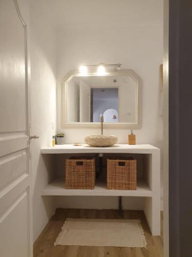 a bathroom with a sink with a mirror and baskets at Casa Alcasar in Benitachell