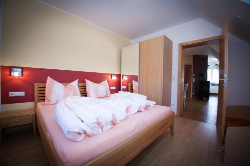 una camera da letto con un letto con lenzuola bianche e cuscini rosa di Weinbau Pronegg vlg. Krainz a Leutschach