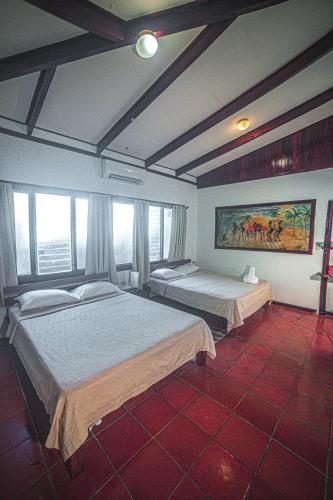 a bedroom with two beds and a painting on the wall at Hotel El Jardin in Montezuma