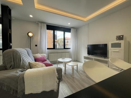 ein Wohnzimmer mit einem Sofa und einem TV in der Unterkunft Apartamento Nuevo con patio, situado en el centro. in Avila