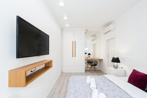 a white bedroom with a flat screen tv on a wall at Central Apartments by Bed&Bath in Kraków
