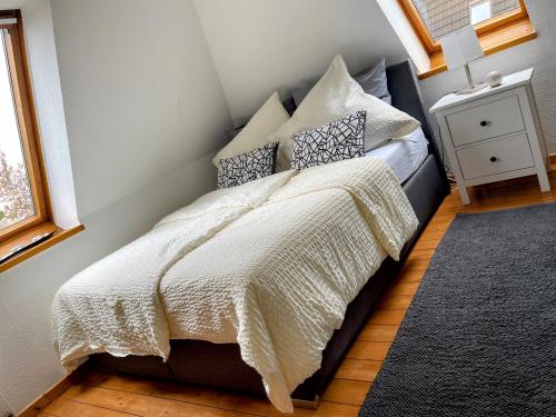 1 dormitorio con cama con edredón y almohadas blancos en *To hus* Wohnung am Rande von Jever, en Jever