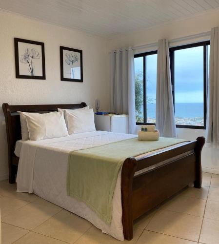 a bedroom with a large bed with large windows at Sentinelas do Mar in Arraial do Cabo