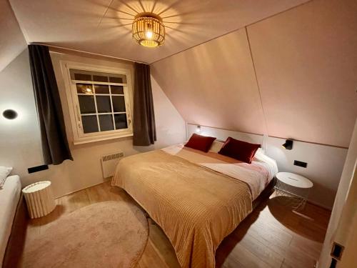 sypialnia z łóżkiem z czerwonymi poduszkami i oknem w obiekcie Heerlijk Huisje Achterhoek w mieście Lievelde