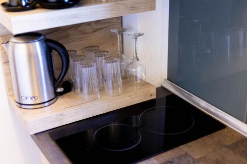 a kitchen counter with glasses on a wooden shelf at Casa Villa, Xenia Paliouri in Paliouri