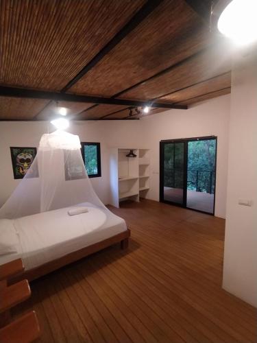 1 dormitorio con cama blanca y suelo de madera en Mola Mola Surf Popoyo en Popoyo