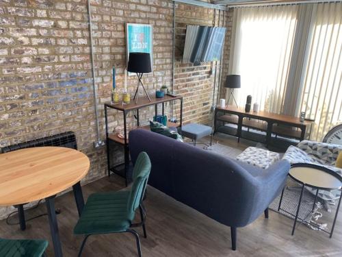 a living room with a couch and tables and a brick wall at The Old Gin Distillery est 1850 in London