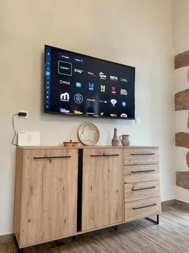 a flat screen tv on a wall above a wooden cabinet at Villa Eftychia Serene Getaway with Hot Tub in a Quiet Location in Kissamos