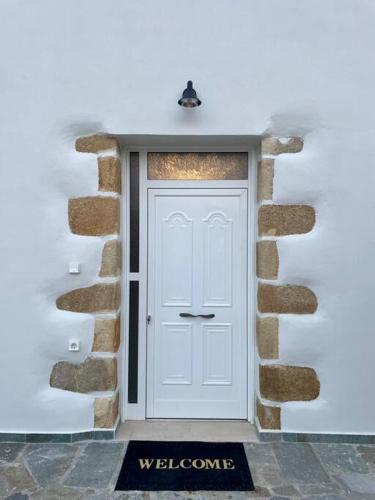 a white door in a stone wall with a welcome mat at Villa Eftychia Serene Getaway with Hot Tub in a Quiet Location in Kissamos