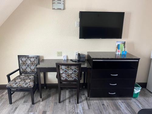 a room with a desk with a television and two chairs at Yosemite Sierra Inn in Oakhurst