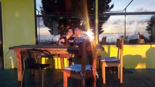 two people are sitting at a wooden table at Hostal y Cabañas Mozart in Puerto Montt