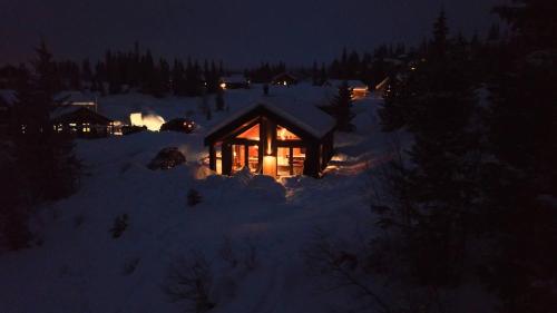 SvingvollにあるUnique cabin with fantastic lake view, sauna, ski & EV outletの夜の雪の中にライトアップされた丸太小屋