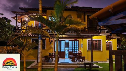 a yellow house with palm trees in front of it at Pousada Casa da Marina in Ilha de Boipeba