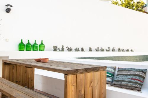 uma mesa de madeira numa varanda com garrafas verdes em Vida na Vila em Vila Nova de Milfontes