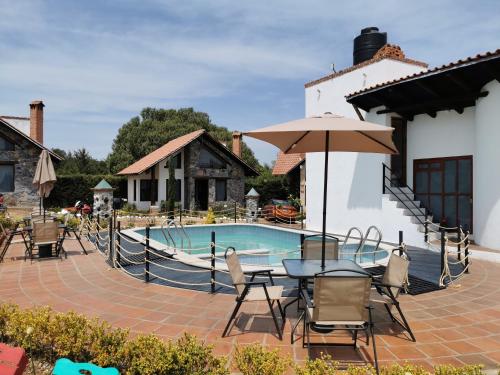 a patio with a table and umbrella next to a pool at Namasté Cabañas, Huasca de Ocampo in Huasca de Ocampo