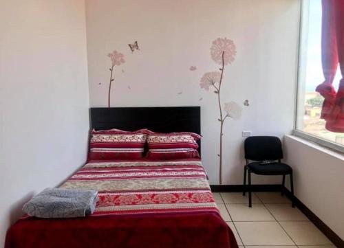 a bedroom with a bed with red sheets and a chair at La Fortuna Roja in San José