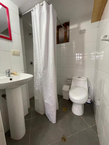 La salle de bains est pourvue d'un rideau de douche blanc et de toilettes. dans l'établissement Yanapanakusun Cusco, à Cusco