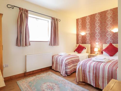 a room with two beds and a window at Barn Owl Cottage in Little Glenham