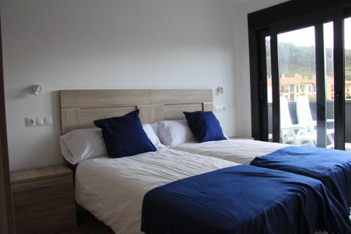 ein Schlafzimmer mit zwei Betten mit blauen Kissen in der Unterkunft La Casina de la Playa in Ribadesella