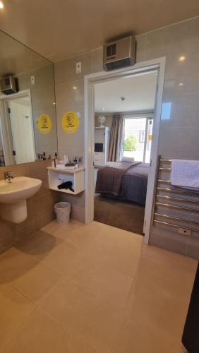 une salle de bain avec un lavabo, un lit et un miroir dans l'établissement THE MEWS Oamaru, à Oamaru