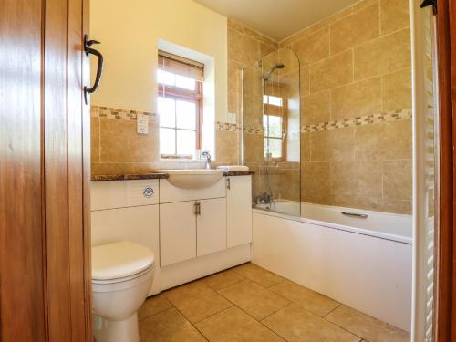 uma casa de banho com um WC, um lavatório e uma banheira em Poppy Cottage em Little Glenham
