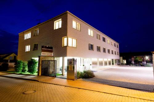 - un grand bâtiment en briques avec des fenêtres éclairées la nuit dans l'établissement Modrá Stodola contactless check-in, à Horoměřice