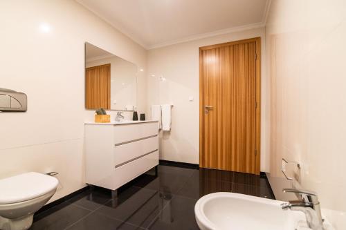 a white bathroom with a toilet and a sink at Furnas Apartment in Furnas