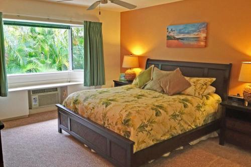 a bedroom with a bed and a large window at Emmalani in Princeville