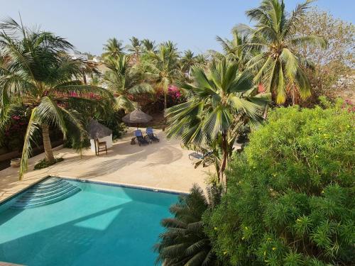 uitzicht op een zwembad met palmbomen bij Le Souimanga Hotel Saly in Saly Portudal