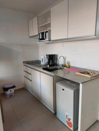 una pequeña cocina con armarios blancos y encimera en Alquiler temporario Rosario en Rosario