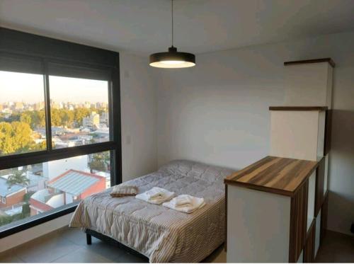 a bedroom with a bed and a large window at Alquiler temporario Rosario in Rosario