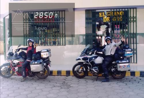 two people on motorcycles parked in front of a store at El Grano De Oro Hotel in Tupiza